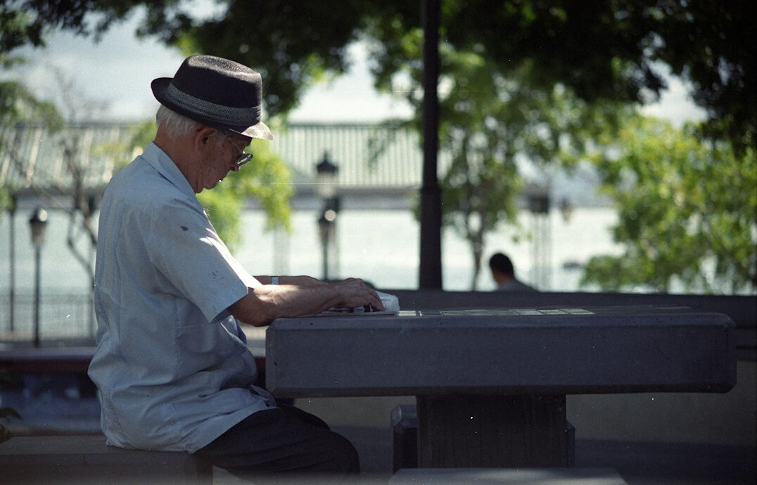 Latin American man in his sixties organizing papers and folders at a wooden dining table