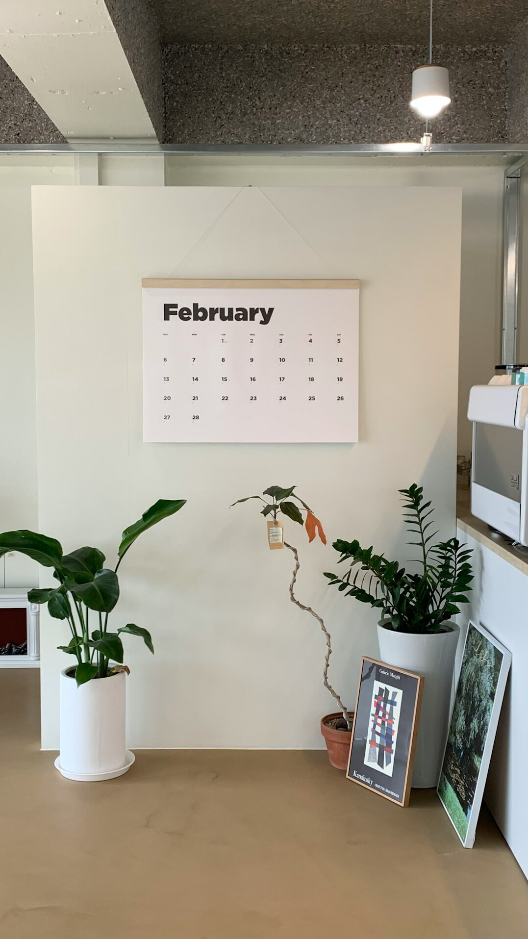 Monthly wall calendar and a budget template with colored sticky notes on a desk